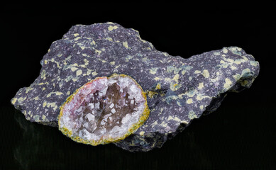 Beautiful crystal gem crystals inside broken agate geode in melaphyre on black background. Volcanic igneous rock sample with small green nodules. Natural uncut mineral stone of Czechia near Nova Paka.