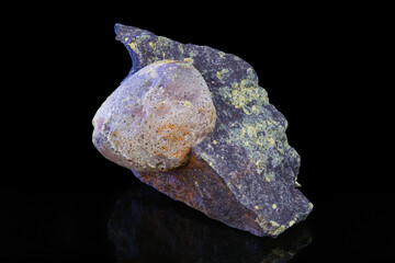 Natural uncut agate precious stone inside melaphyre vesicle on a black background. Closeup a nodule of gem in basalt volcanic igneous rock. Mineral piece with origin near Nova Paka, northeast Bohemia.