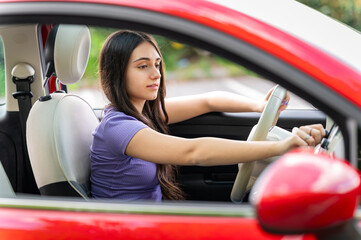 Young woman driving a red car and turning on the radio