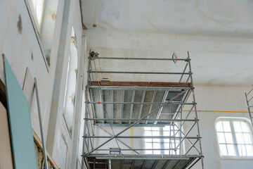 Murs en cours de peinture, avec outils visibles et zones partiellement recouvertes dans un cadre de rénovation ou de décoration intérieure.