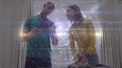 Couple tapping smartphone and projecting technology hologram globe arranging clothes into suitcase - Powered by Adobe