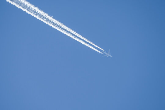 twin engined jet liner aircraft with contrails, in flight at high altitude, clear blue sky