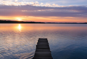 Obraz premium Serene sunset over calm lake with wooden pier reflecting vibrant colors and tranquility