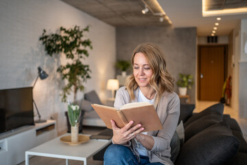 Woman reading a book at home in her living room