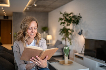 Woman reading a book at home in her living room