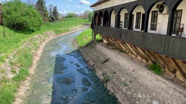 The river, tainted by raw sewage, flows through residential areas, making the water unsafe.