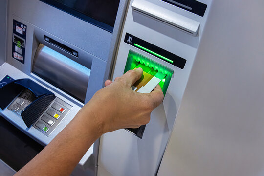 Closeup of a person hand inserting a bank card into an ATM machine slot  for money withdrawal
