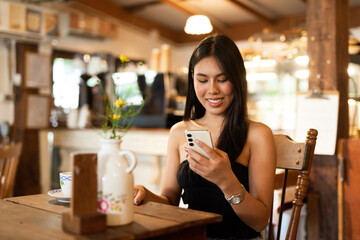 Portrait of beautiful young woman in coffee shop using phone