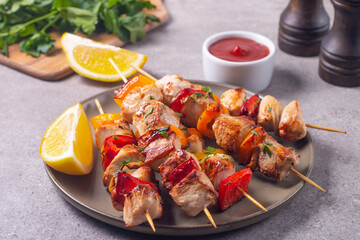 Delicious grilled chicken skewers with capsicum, lemon, salad and ketchup on a plate over the table. Chicken kebab. Healthy food concept.
