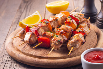 Delicious grilled chicken skewers with capsicum, lemon, salad and ketchup on a plate over the table. Chicken kebab. Healthy food concept.