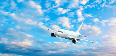 White plane flying in the sky, panoramic view of flying airplane in the sunset sky, travel by air background