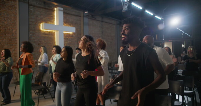 Multicultural congregation clapping and smiling during church worship, illuminated cross in background, expressions of faith, joy, unity, and spiritual devotion