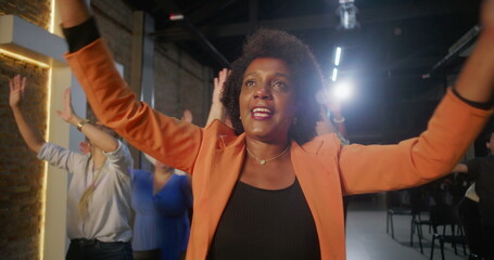 Woman raising arms in joyful worship during church service, glowing cross in background, vibrant...