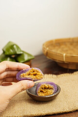 Traditional Indonesian kue bugis with sweet coconut sugar filling, held by hand. Popular sticky...