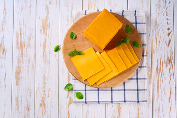 sliced natural cheese cheddar on on a white wooden table, top view.