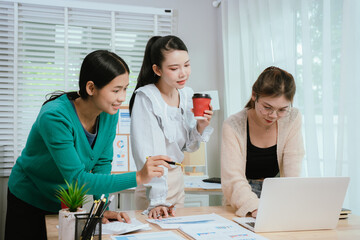 Diverse business team in modern office collaborating on startup strategy, analyzing charts, discussing growth, and planning successful marketing project.