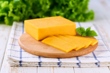 cheddar cheese cut into slices on a light kitchen table, selective focus.