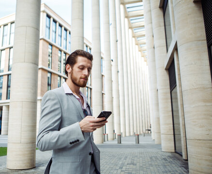 Business, people, tehnology and lifestyle concept: Businessman use smartphone to send voice messages outdoors at downtown.