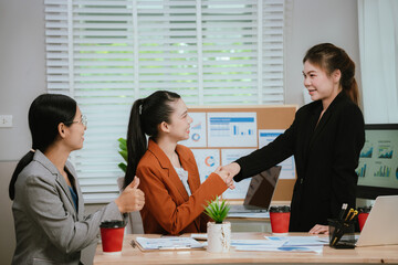 Asian business team collaborating in office, discussing strategy and project planning; professional men and women using laptop during brainstorming meeting.