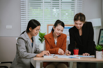 Asian business team collaborating in office, discussing strategy and project planning; professional men and women using laptop during brainstorming meeting.