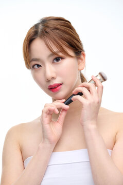 Young Female Applying Makeup with Brush on White Background