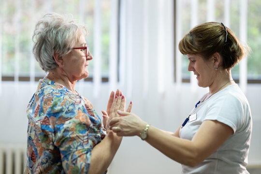 Senior Physical Therapy Session.Senior woman doing physical exercises with the help of a smiling therapist. Concept of elderly rehabilitation and movement recovery.