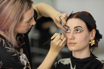 Process of making makeup. Make-up artist working with brush on model face. 
