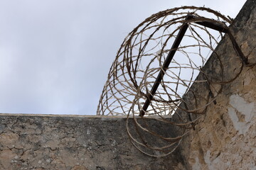 High sandstone prison wall, with razor wire on top, dark moody sky. Background concept. Copy space. Crime, felony, legal system, conviction rate, justice, sentencing, escapees. Youth crime statistics.
