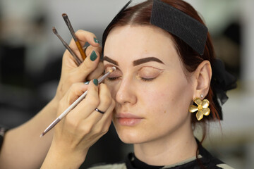 Obraz premium Process of making makeup. Make-up artist working with brush on model face. 