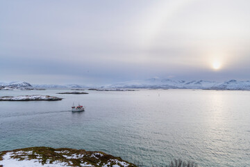 Fisherman sails his boat out to sea under overcast skies, the veil clouds create a dull weather on...