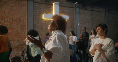 Diverse congregation in worship, hands over heart and raised in praise, glowing cross in background, collective spiritual connection, unity, and faith in sacred church service