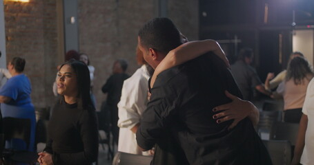 Diverse congregation members exchanging hugs and smiles in a modern church setting, creating a sense of community, connection, and shared spirituality