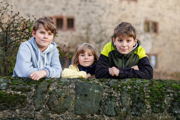 Little toddler girl and two kids boys holding selfmade lanterns with candle for St. Martin...