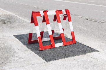 Red road barriers on asphalt. Traffic warning signs at street repair. Urban construction zone....