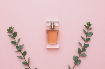 Amber Perfume Bottle with Eucalyptus Leaves on Pastel Pink Background, Elegant Luxury Fragrance