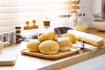 The croissant bread is placed on a wooden tray in the kitchen.