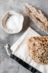 Flat lay of natural bathroom essentials: c, eco toothbrushes and bristle brushes, sea sponge, sea salt, washcloth. Zero-waste, plastic-free, beautifully styled in a calm, neutral setting