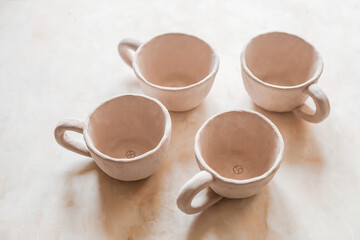 Handmade unglazed ceramic cups in natural clay color on beige background. Artisan pottery with organic texture and minimalist aesthetic. Slow living and modern rustic style
