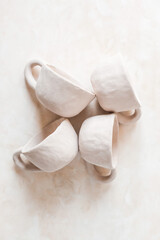 Handmade unglazed ceramic cups in natural clay color on beige background. Artisan pottery with organic texture and minimalist aesthetic. Slow living and modern rustic style