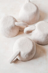 Handmade unglazed ceramic cups in natural clay color on beige background. Artisan pottery with organic texture and minimalist aesthetic. Slow living and modern rustic style