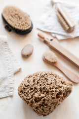 Flat lay of natural bathroom essentials: c, eco toothbrushes and bristle brushes, sea sponge, sea salt, washcloth. Zero-waste, plastic-free, beautifully styled in a calm, neutral setting