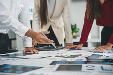 Business people reviewing financial reports and pointing at charts during a meeting in a modern...