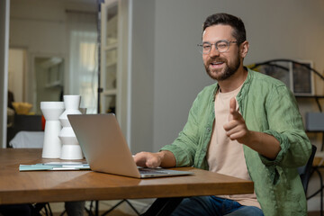Obraz premium Man sitting at desk working on laptop showing thumb up like gesture