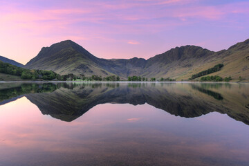 Beautiful spring sunrise at Buttermere with mirror-like reflections in calm water. Lake District...