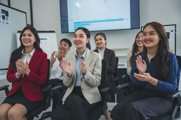 Obraz premium Group of asian businesspeople sitting and clapping hands after successful meeting or presentation in modern office