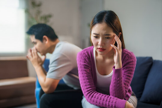 Young asian couple having relationship problems, arguing and sitting back to back on sofa at home