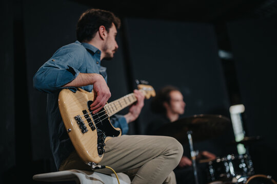 Musicians rehearsing with focus on a bass guitarist during a band practice session, showcasing teamwork and performance preparation for an upcoming live concert or event. - Powered by Adobe