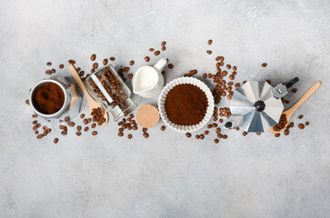 Coffee composition with ground coffee, beans, moka pot, milk, and wooden utensils on gray...