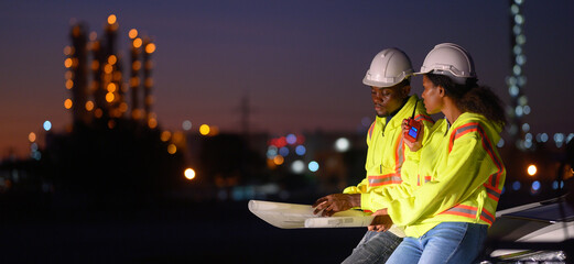 Male and female engineers inspect the integrity and safety of a gas pipeline at night.