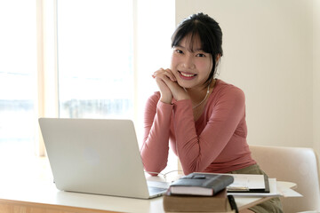 Young woman smiling sitting at her desk  and talking on the phone